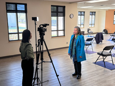 a faculty member is interviewed by a reporter in an exercise research space