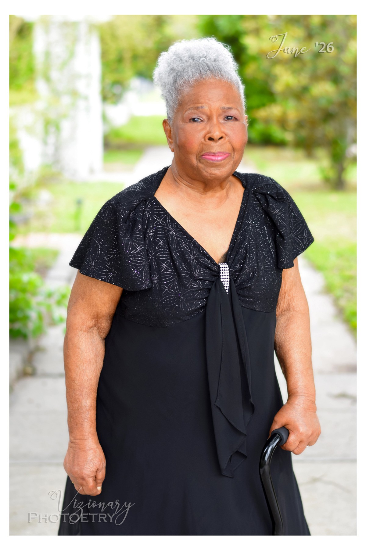 Ms. Love, a centenarian woman of color stands outdoors in Sunday dress