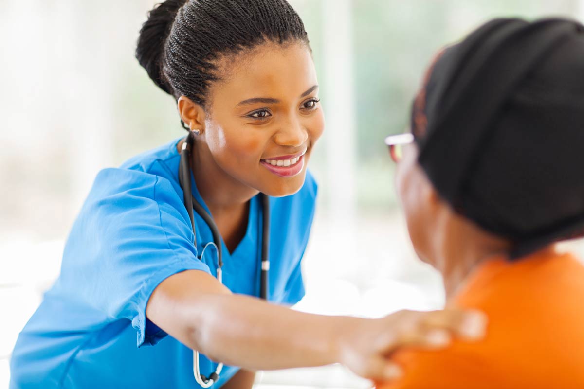 Medical professional, woman of color, helping an older adult woman of color