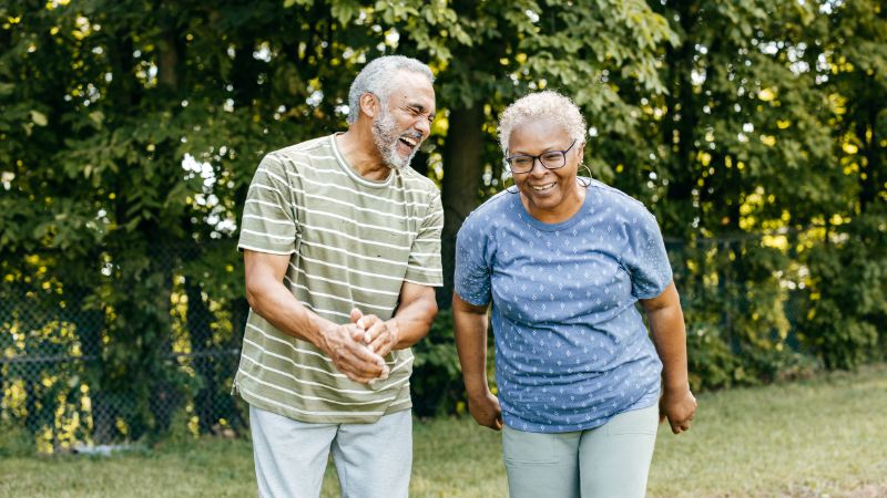 photo of two older adults of color walking together and smiling outdoors