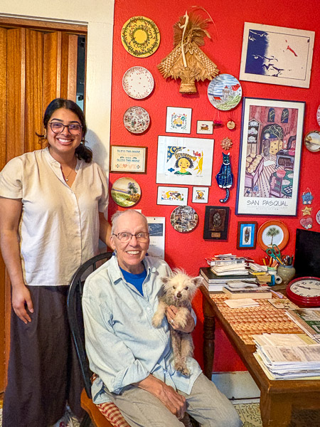 Medical student Annika Nambiar stands with older adult Bets Anderson in her home with her pet dog 