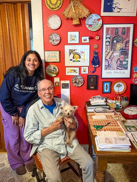 A medical student, (Arati Bendapudi) poses with older adult, (Bets Anderson) and her pet dog in her home