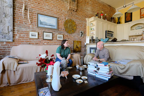 Uli Budelmann a student interviews an older adult in his home with books and art