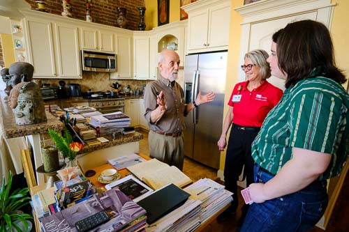 Ulli Budelmann an older man gestures as he speaks with two women in his home
