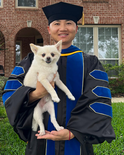 photo of man in scholar graduation gown with dog