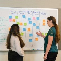 two woman at whiteboard