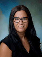 Professional photo of Dr. Taylor smiling, with long dark hair and wearing a black shirt and black glasses