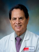 Sharma rofessional photo of Dr. Sharma, who has short dark hair and is wearing a gray shirt, purple tie and white UTMB lab coat