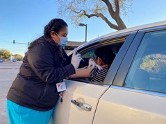 Female in scrubs giving vaccine to patient sitting in card as part of CPRIT Clinical Trial