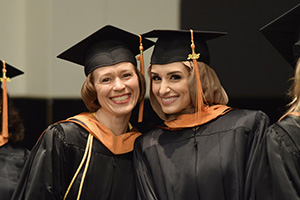 Two nursing graduates pose together, smiling