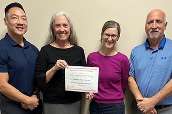 Drs. Tony Chao, Susan Klappa, Laura Opperman, and Rodney Welsh pose together. Dr. Klappa holds a paper certificate recognizing their PLTI Innovator Award.