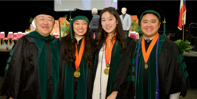 Four JSSOM grads in regalia pose together, smiling for the camera.
