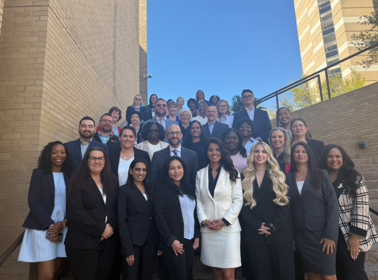 Graduating Doctor of Nursing Practice students, dressed in business attire, gather on the steps of Levin Hall.