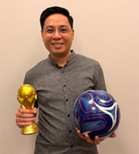 Faculty-staff winner Winner Thang Nguyen-Tien holds a trophy in his right hand and a soccer ball in his left