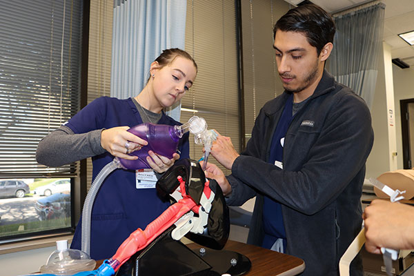 Two respiratory care students practice intubation using a simulation tool