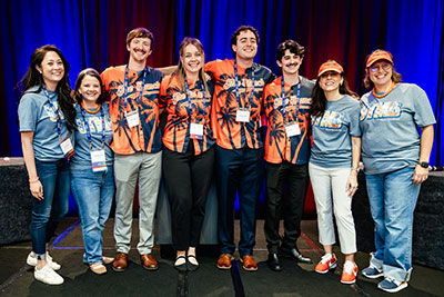 UTMB attendees line up for a posed photo at the TxANA Convention. Two on each end are wearing light blue UTMB T-shirts and the four in the center have on orange tropical print shirts.