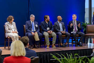 Panelists sit in a row on stage