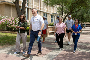 A group of UTMB employees walks along the sidewalk next to the Galveston National Lab.