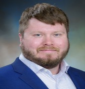 Picture of a man with brown hair wearing a blue suit