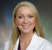 Picture of a woman smiling with blonde hair wearing a white lab coat