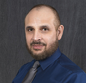 Picture of a man wearing a blue shirt and grey tie