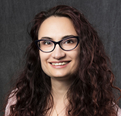 Picture of a woman with long curly brown hair and glasses smiling