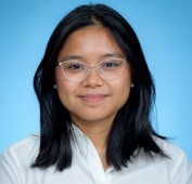 Picture of a young woman wearing glasses, smiling, wearing a white shirt