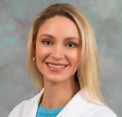 Picture of a women smiling with long blonde hair wearing a white lab coat