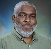 Picture of a man with grey hair wearing a green button down shirt