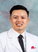 Image of a man smiling in a white lab coat and black tie
