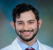 Picture of a man smiling wearing a white lab coat