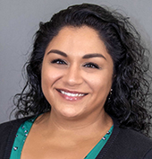 Picture of a woman with dark, curly hair wearing a black shirt with teal collar