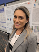 Picture of a woman smiling wearing a suit standing in front of a poster