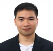 Picture of a man with dark hair wearing a white shirt with a black jacket standing in front of a white background