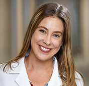 Picture of a woman smiling with long brown hair wearing a lab coat