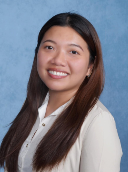 Image of a lady smiling with long, dark hair wearing a white shirt