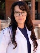 Image of a lady in a white lab coat with glasses outside