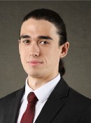 Picture of a man in a dark suit, white shirt, burgundy tie with his hair slicked back