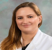 Picture of a woman with long brown hair wearing a lab coat smiling