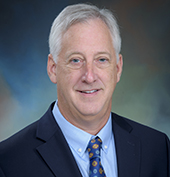 Picture of a man wearing a dark suit smiling