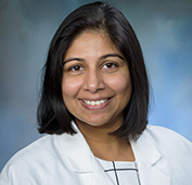 Picture of a woman wearing a white lab coat with short dark hair