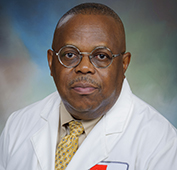 Picture of a man wearing a white lab coat and yellow tie and glasses
