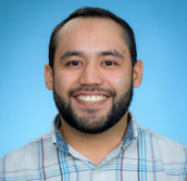 Picture of a man smiling  in front of a blue background