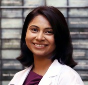 Picture of a woman smiling wearing a white lab coat and maroon shirt