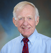 Picture of a man smiling wearing a blue shirt and red tie