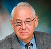 Picture of a man wearing a grey suit, blue shirt and glasses