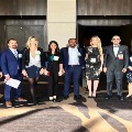 Group of UTMB pathology residents and faculty standing together in a conference venue hallway, wearing professional attire and name badges, gathered for a group photo during a medical meeting.