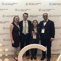 Group of UTMB pathology residents standing together in front of a College of American Pathologists backdrop, wearing conference badges and posing during a professional medical meeting.