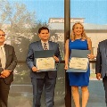 UTMB pathology residents standing on a stage holding certificates during a conference award presentation, with a projected backdrop behind them at a professional medical meeting.