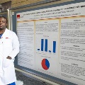 UTMB pathology resident Paul presenting research during a conference poster session, discussing findings with attendees in a professional academic setting.